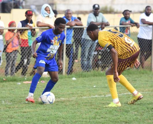 Clarendon College’s Anthony Reid (left) tries to shake the attentions of Manchester High’s Jequil Forbes during their ISSA Ben Francis Cup knockout quarter-finals football match at the Manchester playing field yesterday.