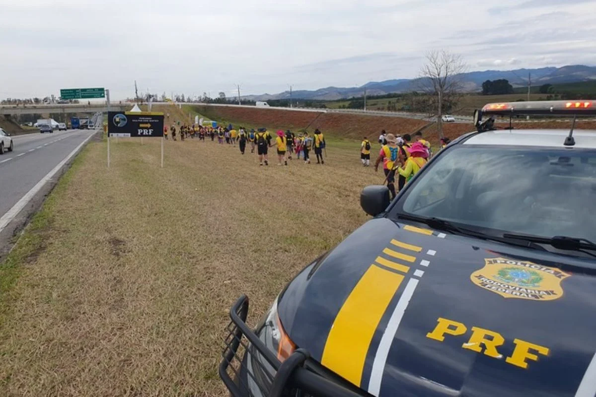 Imagens mostram romeiros à beira da estrada, acompanhados por viatura da PRF