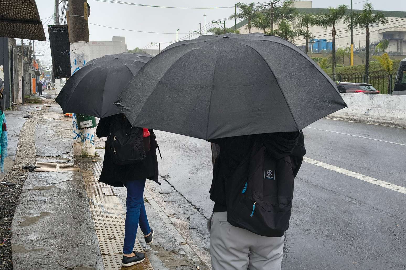 Pedestres se protegem da chuva na Avenida Interlagos, no Jardim Cons&oacute;rcio, zona sul de S&atilde;o Paulo, nesta sexta-feira, 2 de outubro de 2026